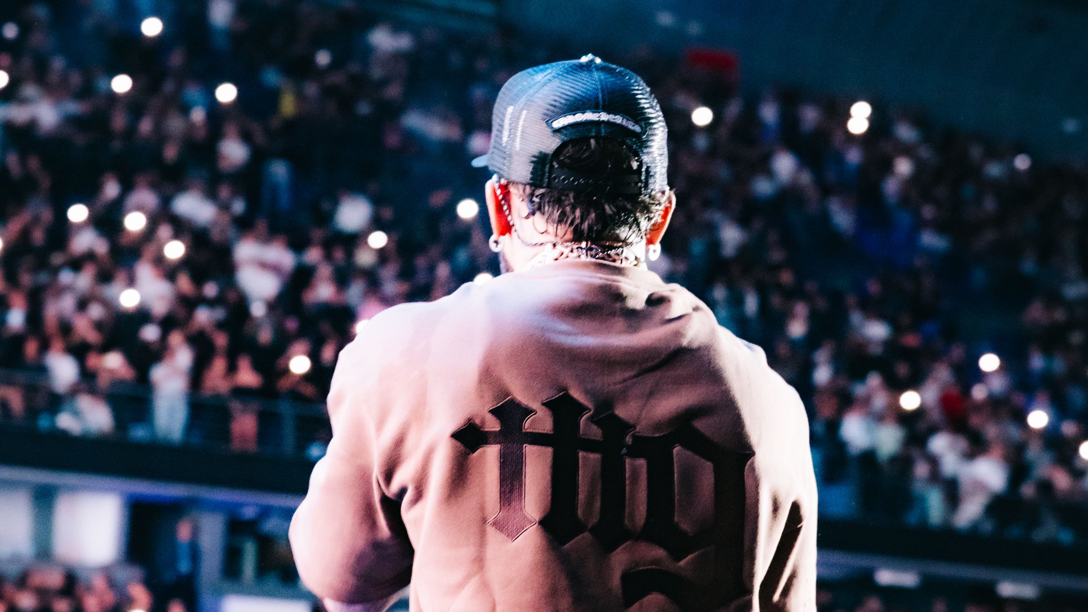 Bryant Myers with his back to the camera, the embroidered mg facing the Movistar Arena crowd