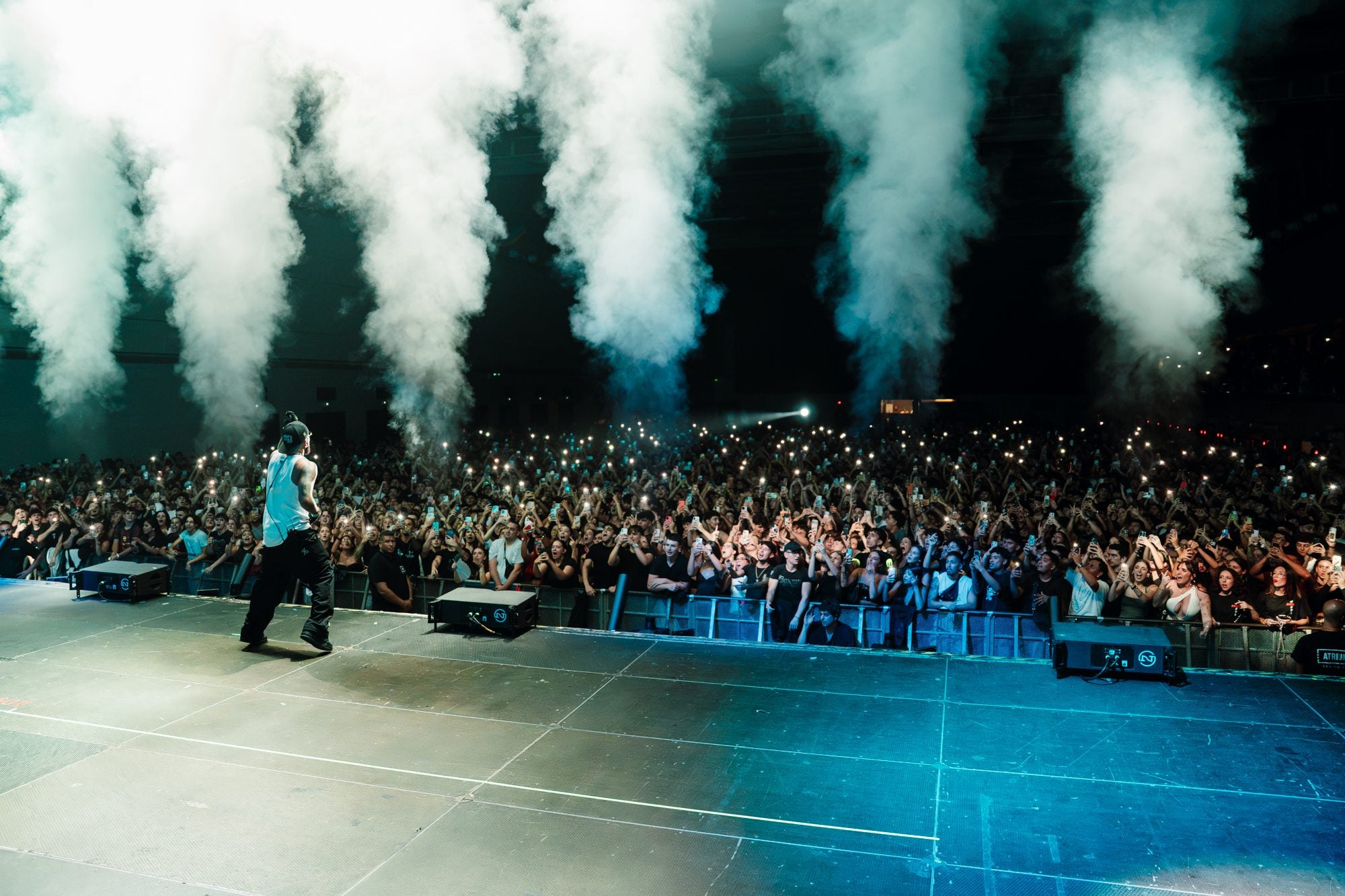 Bryant Myers en el escenario entre cinco columnas de humo blanco